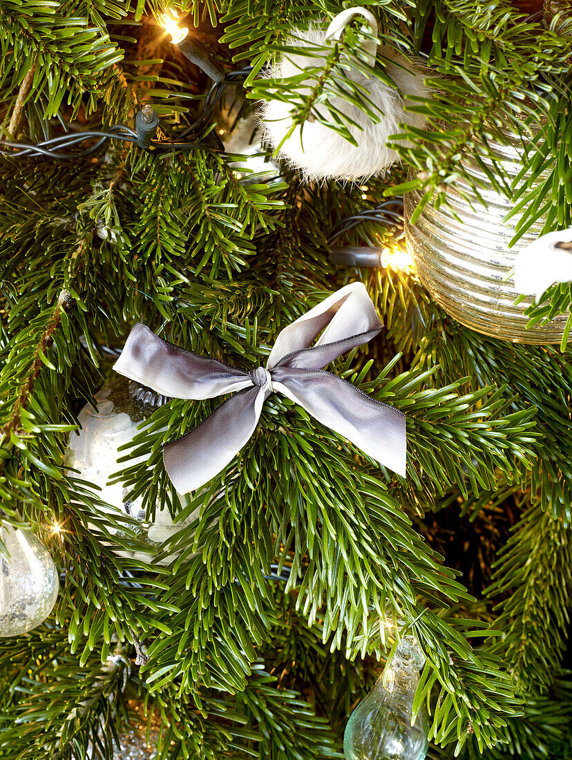 Silberne Schleife und Lichterketten mit Kugeln am Weihnachtsbaum im Londoner Haus England UK