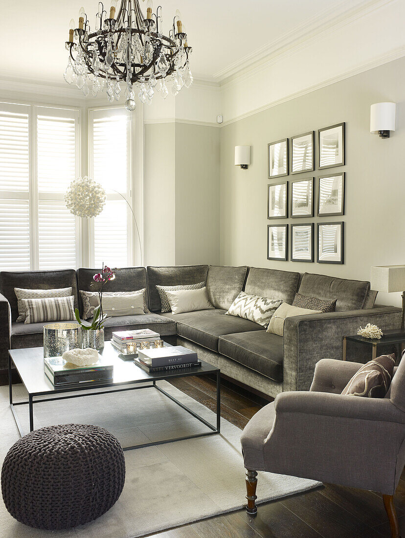 Glaskronleuchter im Wohnzimmer mit grauem Sofa und gerahmten Fotodrucken im Wohnzimmer eines Hauses in London England UK
