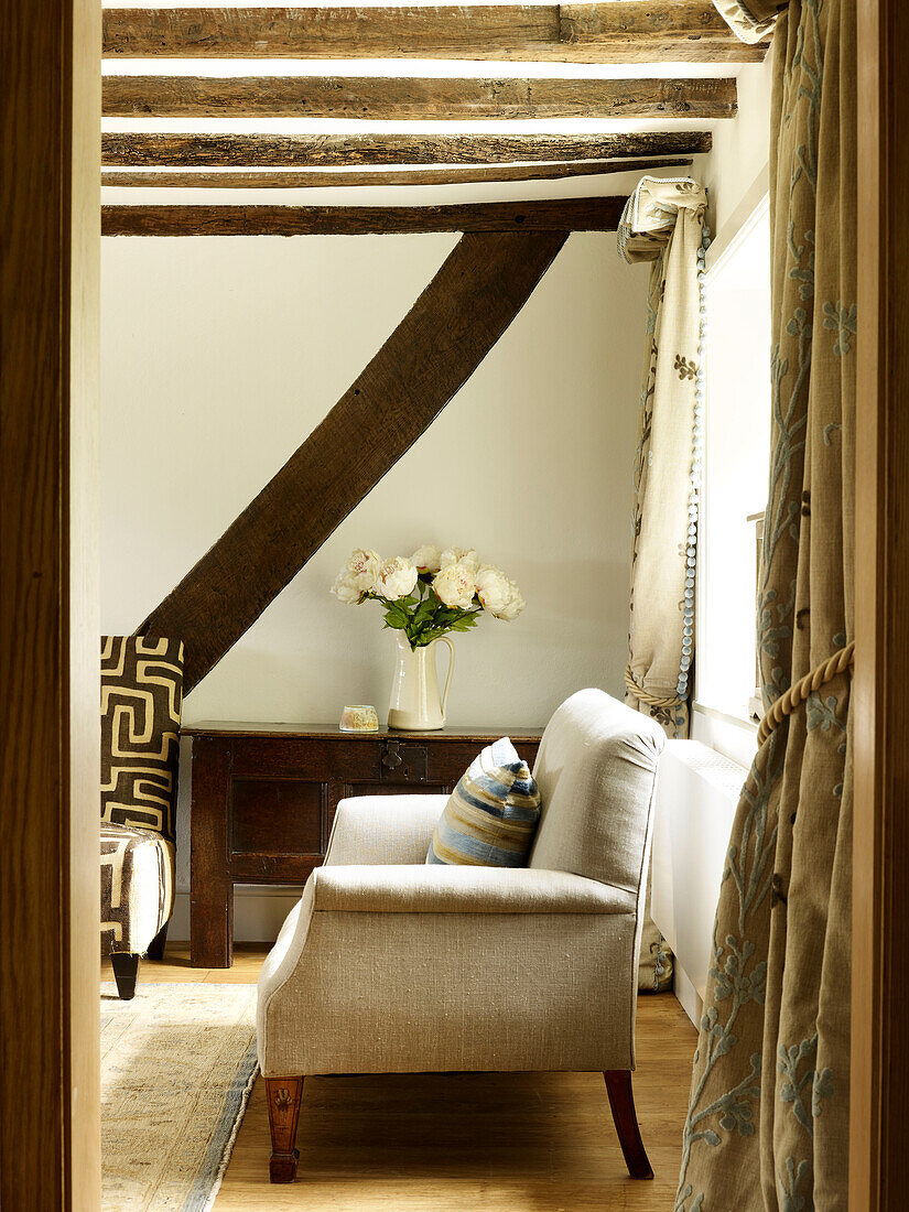 Linen sofa with cut flowers on sideboard in timber-framed West Sussex farmhouse, England, UK