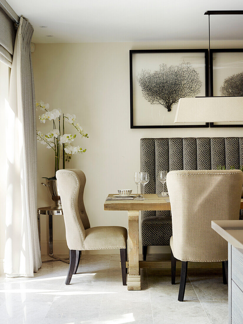 Upholstered chairs with orchid at dining table in London townhouse, UK