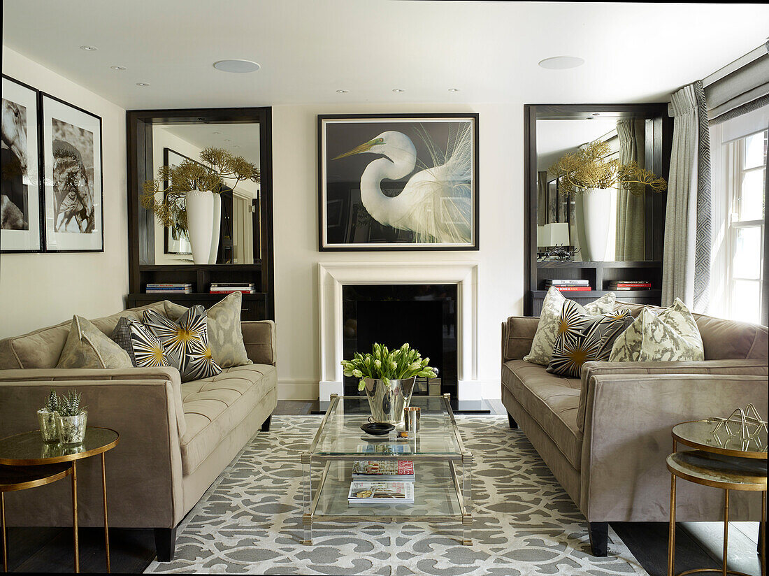 Pair of sofas with glass coffee table and mirrored alcoves in London townhouse, UK