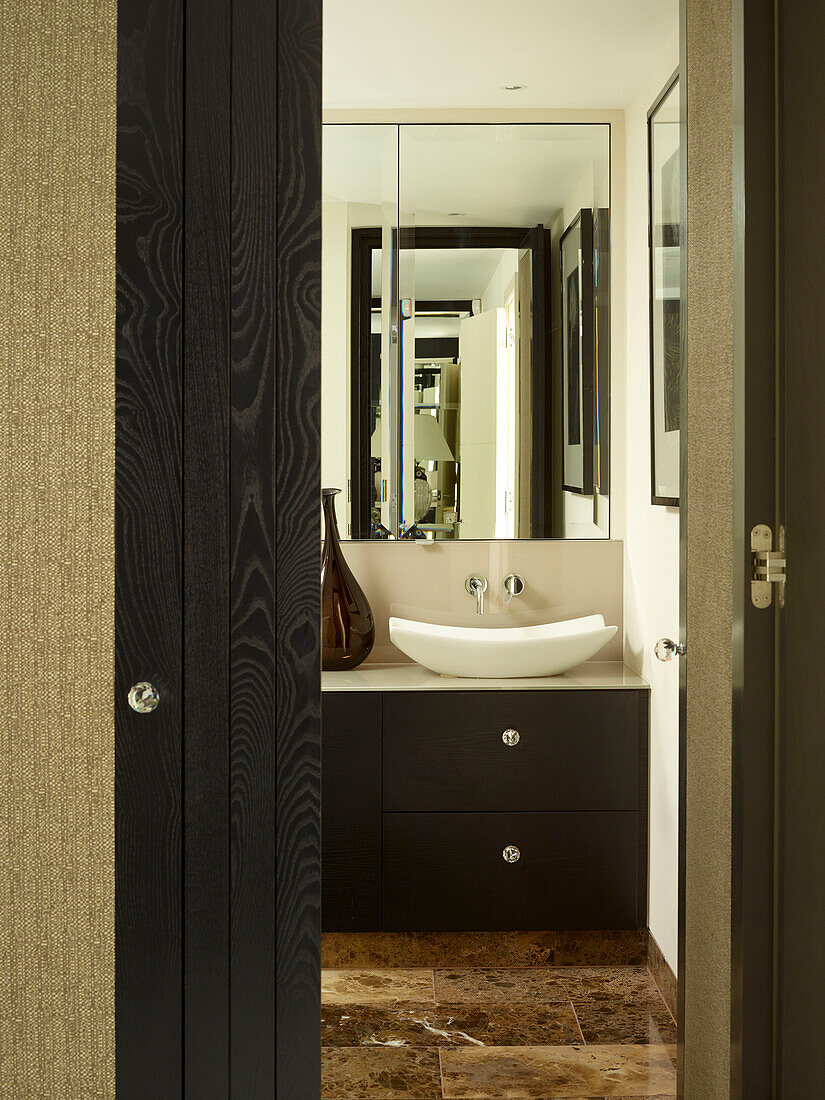 Blick durch die Tür zum Badezimmer mit Spiegel über dem Waschbecken in einem Londoner Stadthaus, UK
