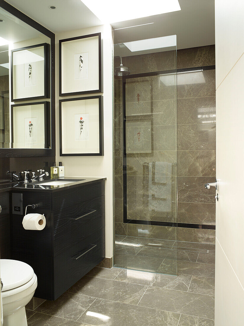 Black wash stand with framed artwork and glass shower cubicle in London townhouse, UK