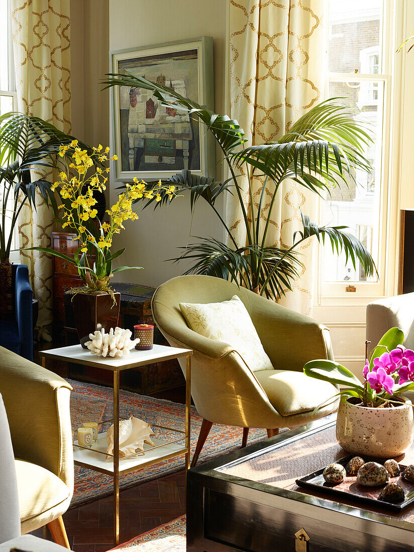 Gold armchair and plants with side table in London townhouse apartment, UK