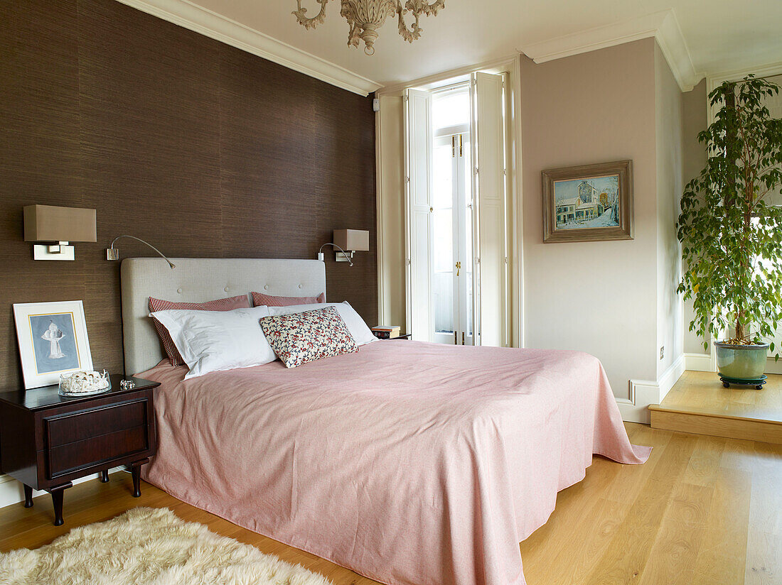 Houseplant in split-level bedroom with window shutters and pink bedspread, London townhouse apartment, UK