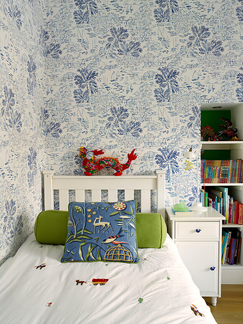 Drache am Kopfteil eines Einzelbetts mit Palmentapete im Zimmer eines Jungen, Londoner Stadthaus, UK