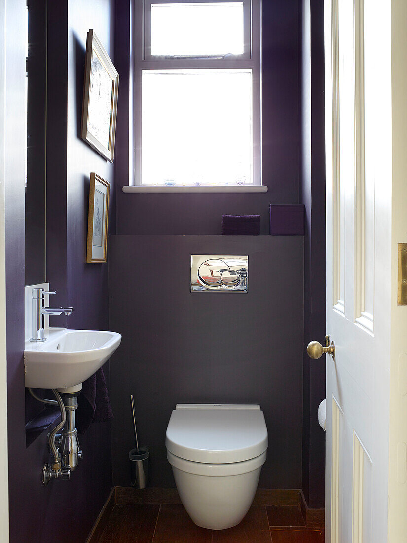 Small purple bathroom with uncurtained window in London townhouse apartment, UK