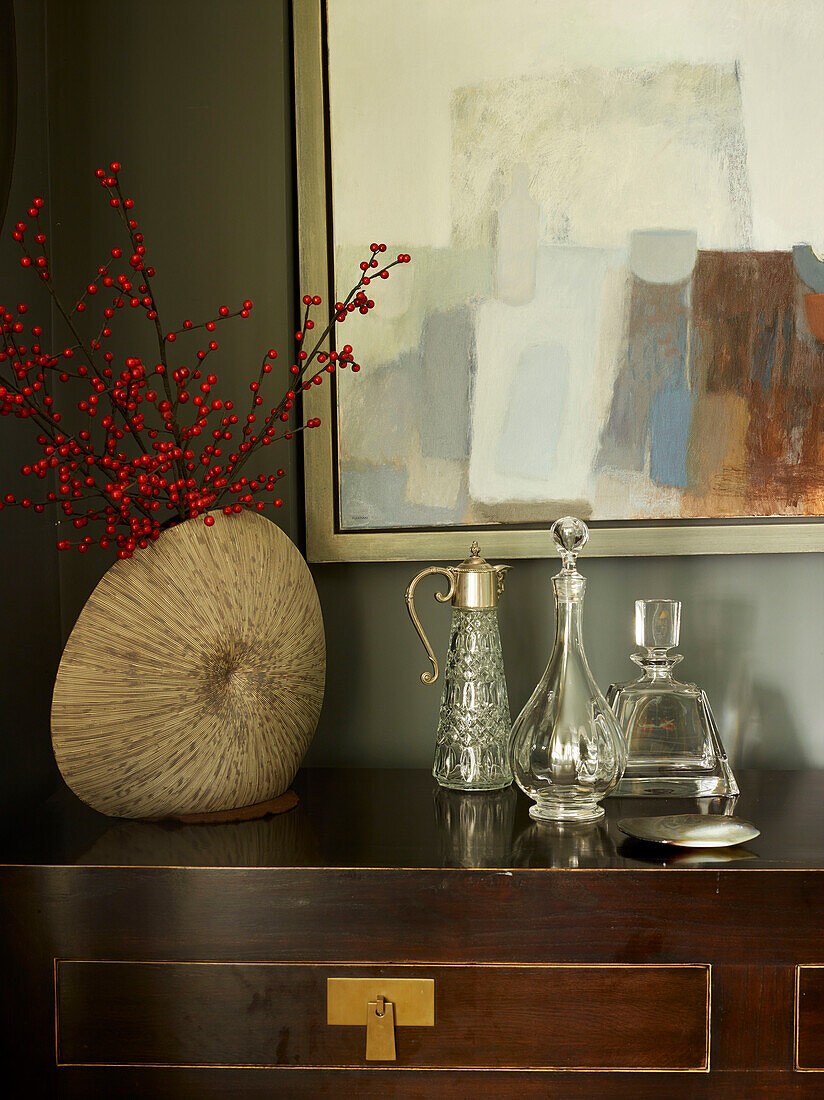 Glassware and berries with artwork canvas on polishes wooden sideboard in London townhouse, UK