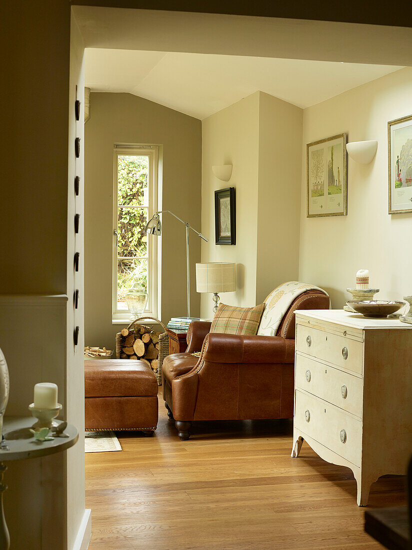 Brown leather armchair and footstool with chest of drawers in Oxfordshire cottage, England, UK