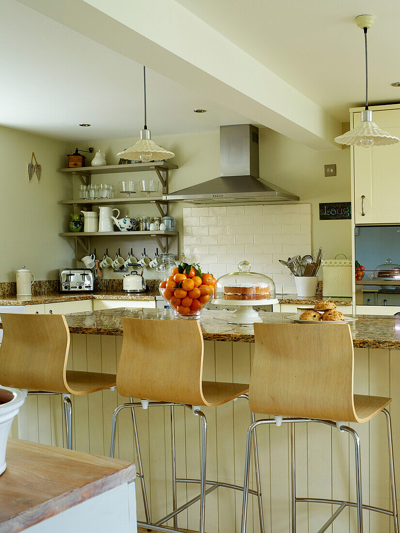 Wood and chrome stools at breakfast bar in open plan Oxfordshire kitchen, England, UK