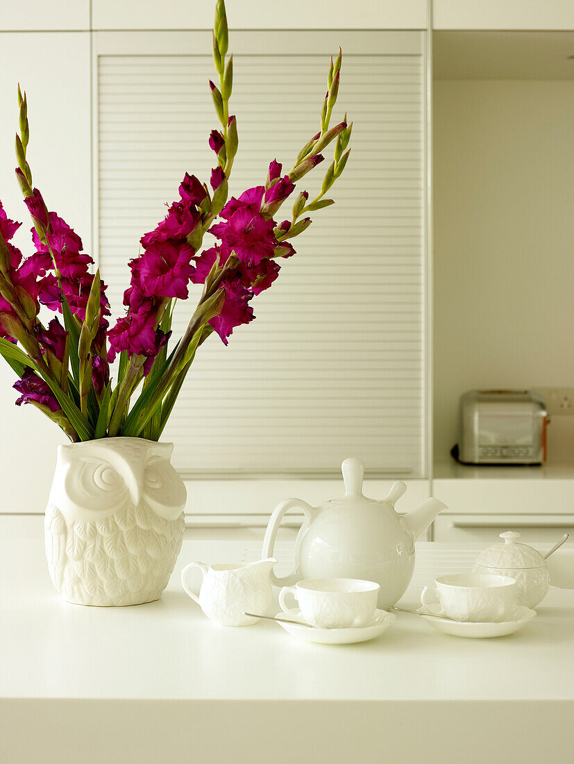 Gladiolen in Eulenvase mit Teeservice in weißer Küche eines Londoner Hauses, UK