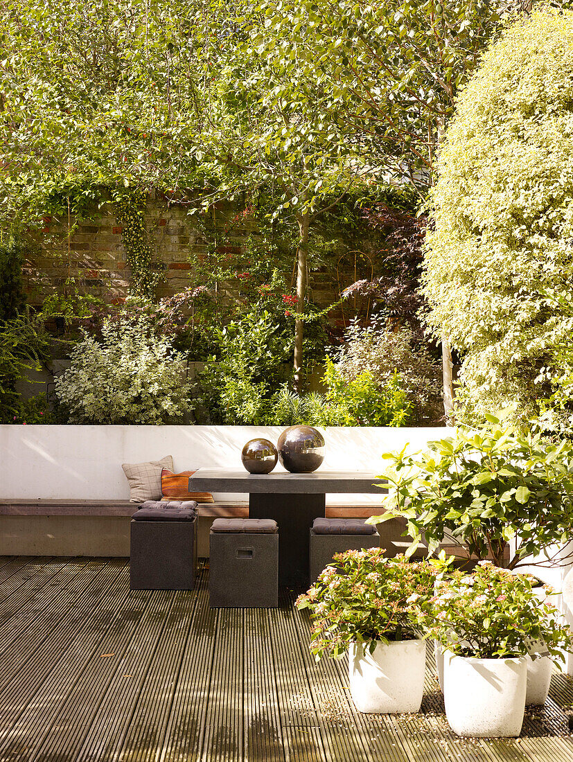 Sitzbank und Hocker mit Gartenornamenten in einem ummauerten Londoner Innenhof, UK