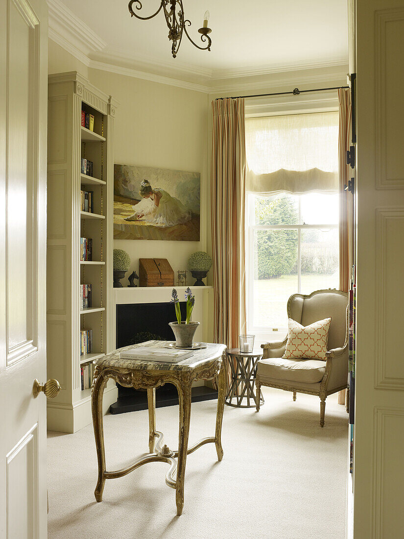 Beistelltisch und Bücherregal mit Marmorplatte und Sessel in einem Landhaus in East Sussex, England, UK