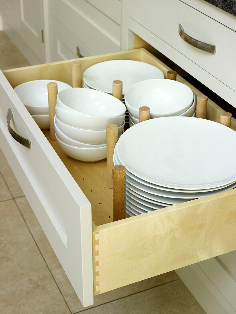 Weiße Keramikteller und -schüsseln in einer Küchenschublade in Nottinghamshire, England