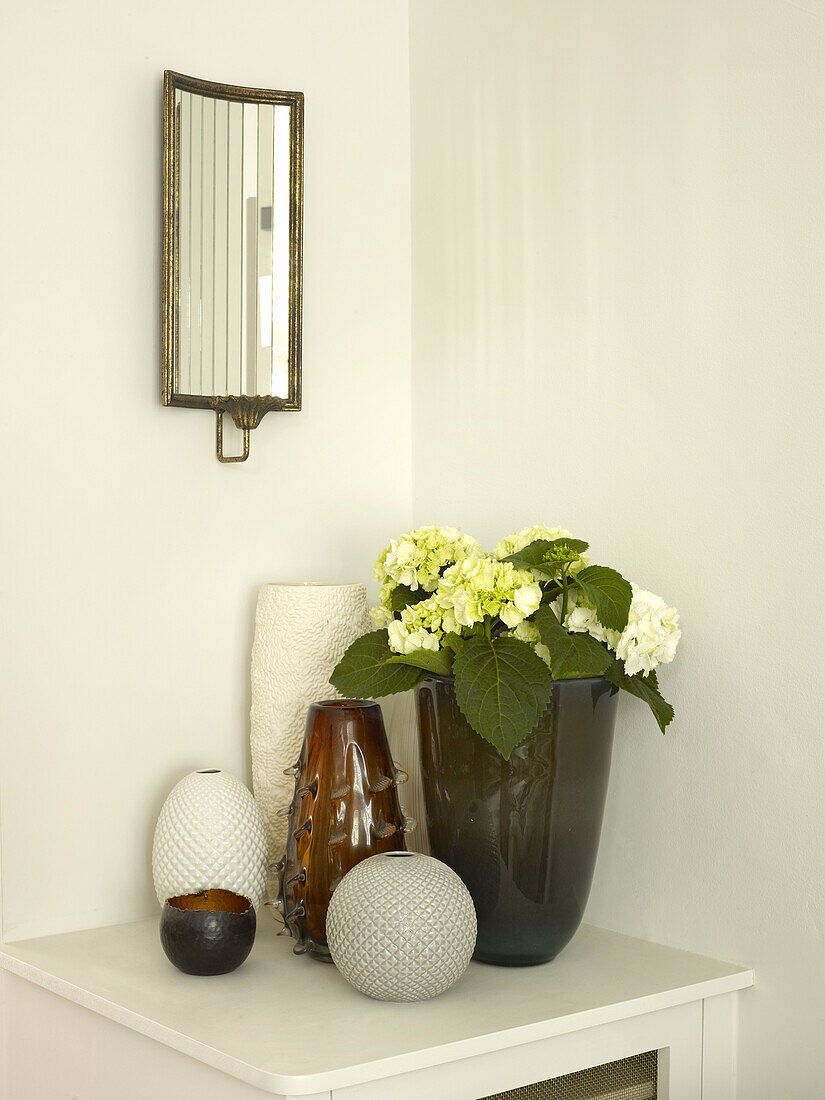 Cut flowers and vases with vintage mirror on side table in North London townhouse England UK