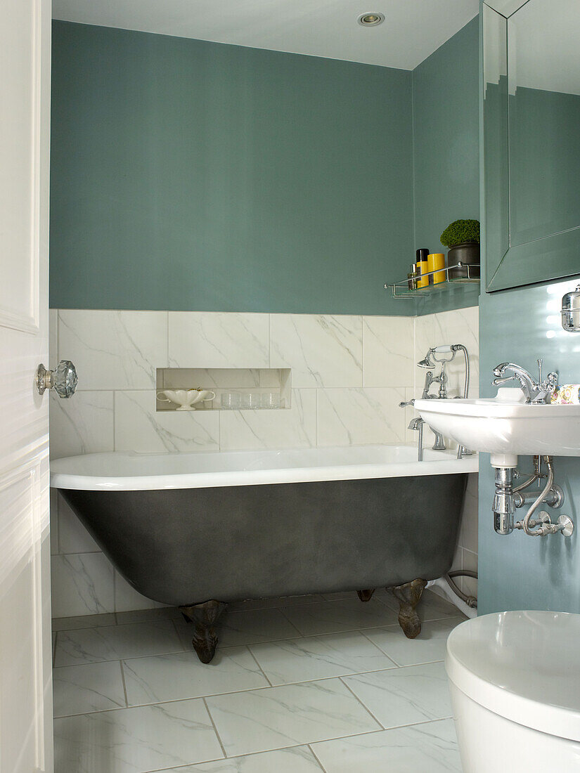 Freistehende Badewanne mit Marmorspritzschutz im türkisfarbenen Badezimmer eines Stadthauses im Norden Londons, England UK