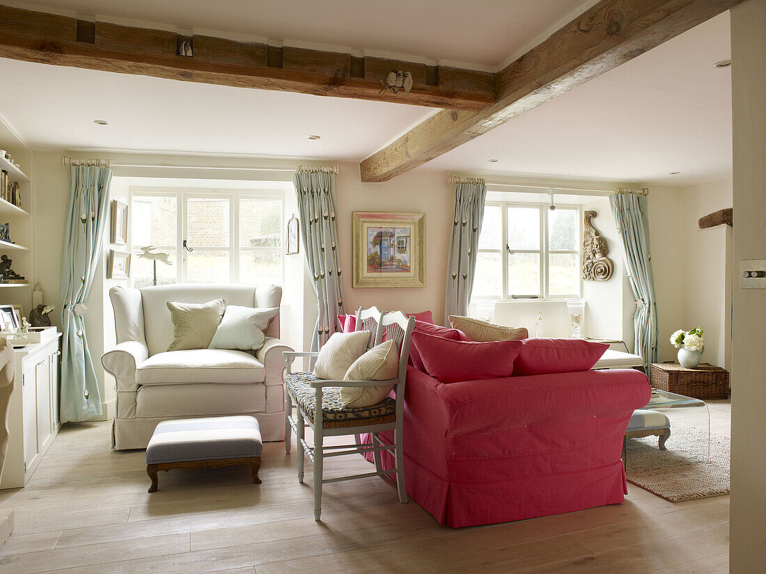 Pink sofa with armchair and footstool at window of Nottinghamshire living room England UK