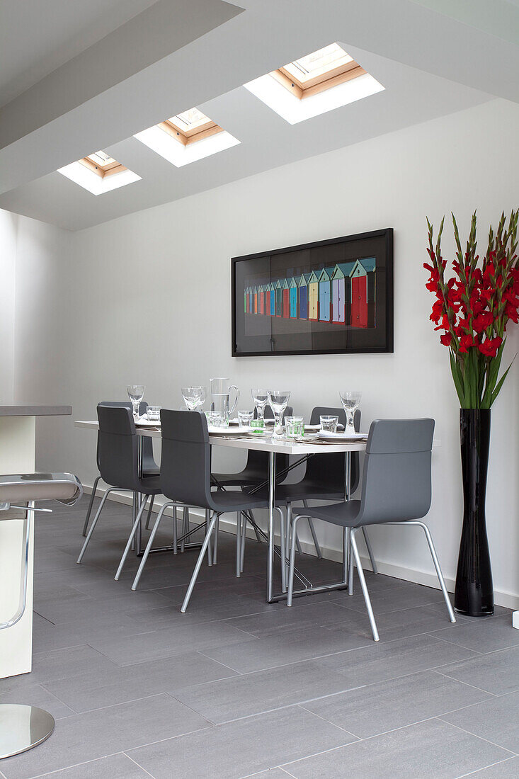 Großes Blumenarrangement und Esstisch unter Oberlicht in Küchenerweiterung eines modernen Hauses in London, England, UK