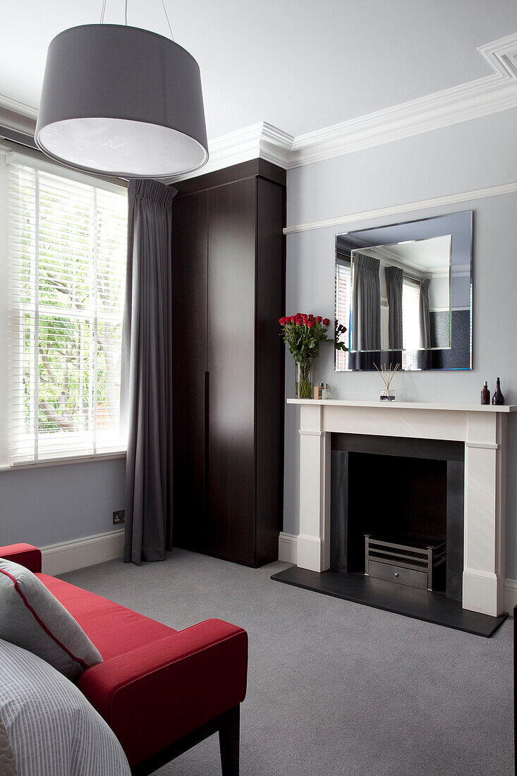 Dark wood wardrobe with mirror over fireplace in contemporary London home, England, UK