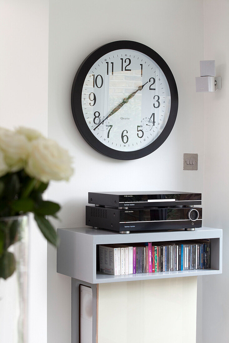 Stereoanlage und Musiksammlung auf einem Wandregal unter der Uhr in einem modernen Haus in London, England, Vereinigtes Königreich