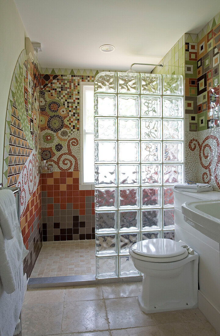 Duschabtrennung aus Glasbausteinen und mosaikgeflieste Wand in einem Badezimmer in Cambridgeshire UK