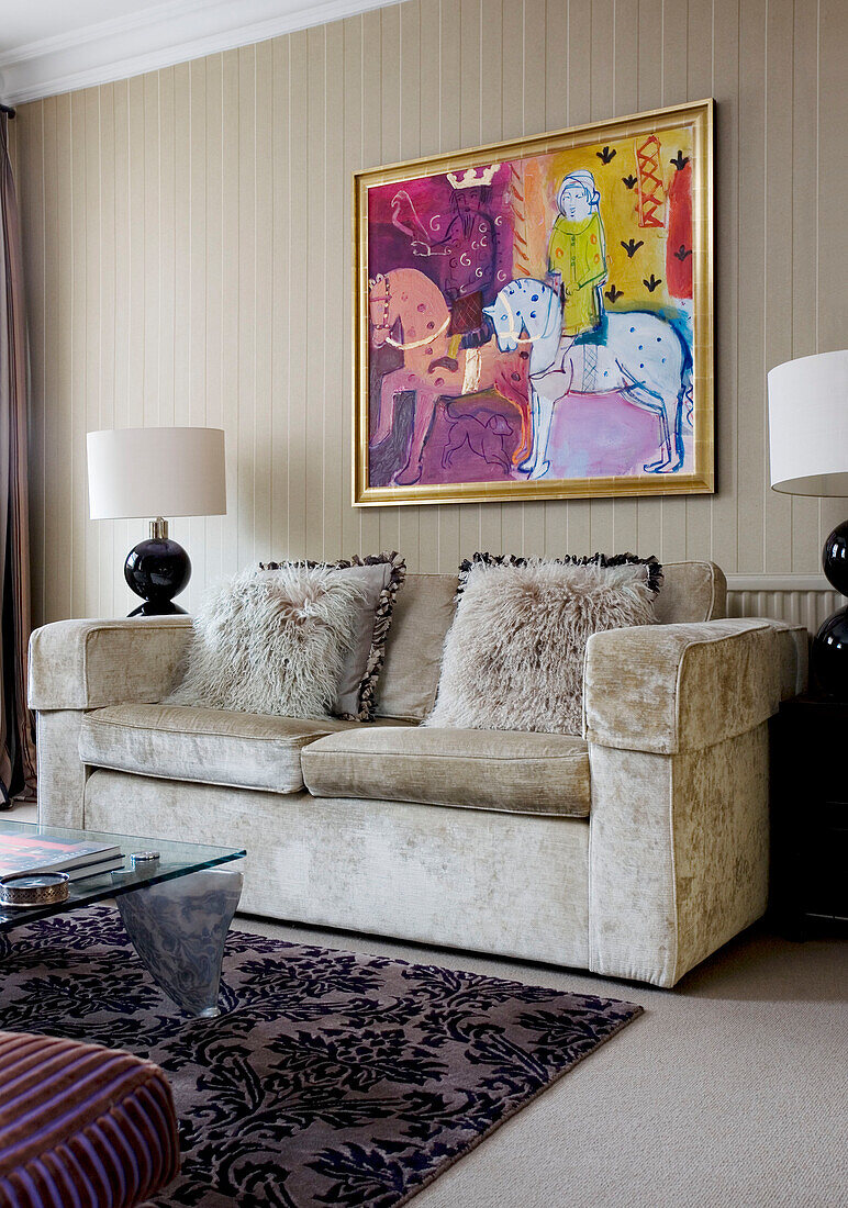Straußenfederkissen auf beigem Sofa unter moderner Kunst