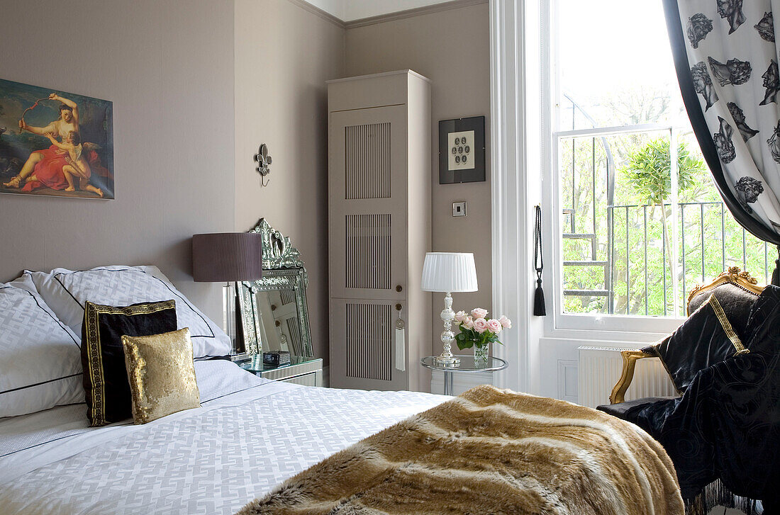 Goldene Kissen auf einem Bett mit bemaltem Schrank in einem Haus in Hove, East Sussex, Großbritannien