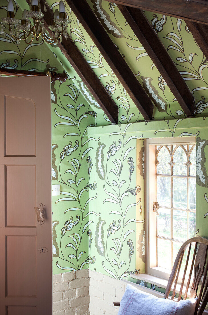 Beamed ceiling with green floral wallpaper and pink door detail, timber framed cottage, Kent England, UK