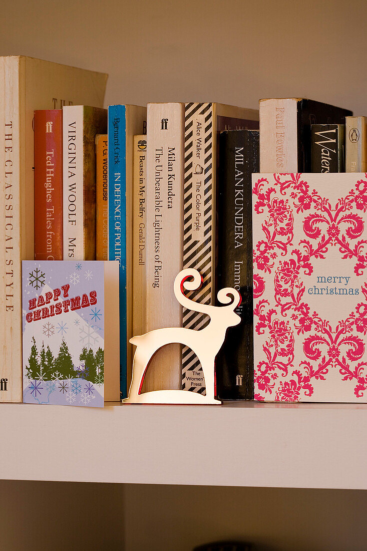 Books and Christmas cards on bookcase in the living room of London home UK