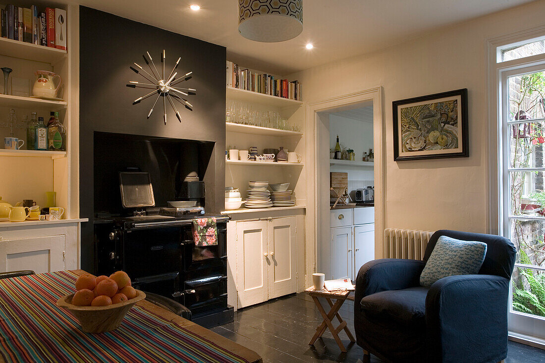 Wanduhr und Sessel in der Küche eines Londoner Hauses UK