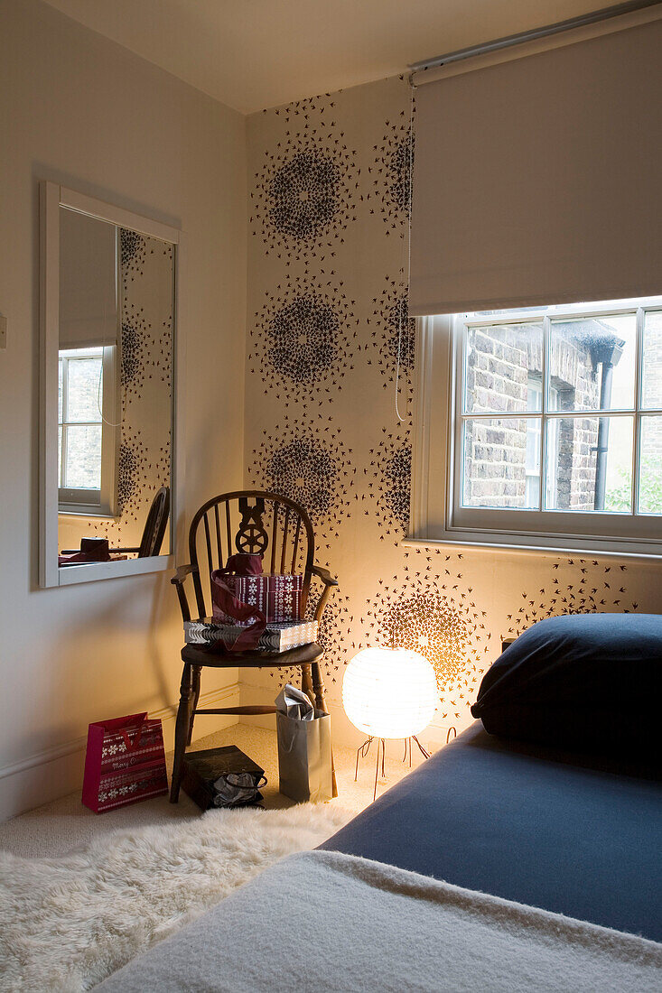 Beleuchtete Lampe und Stuhl mit rechteckigem Spiegel im Schlafzimmer eines Londoner Hauses UK