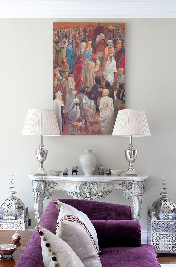 Silver lamps and artwork with purple sofa in living room of country house