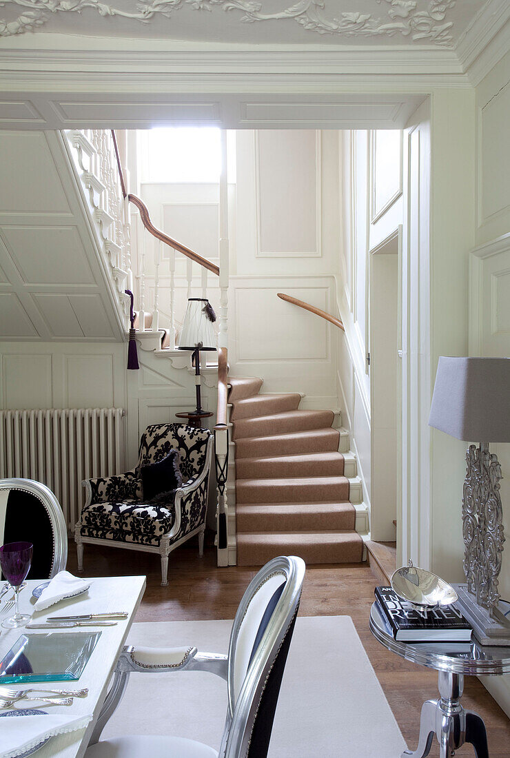 Schwarz gemusterter gepolsterter Stuhl und Treppe im offenen Esszimmer einer Wohnung