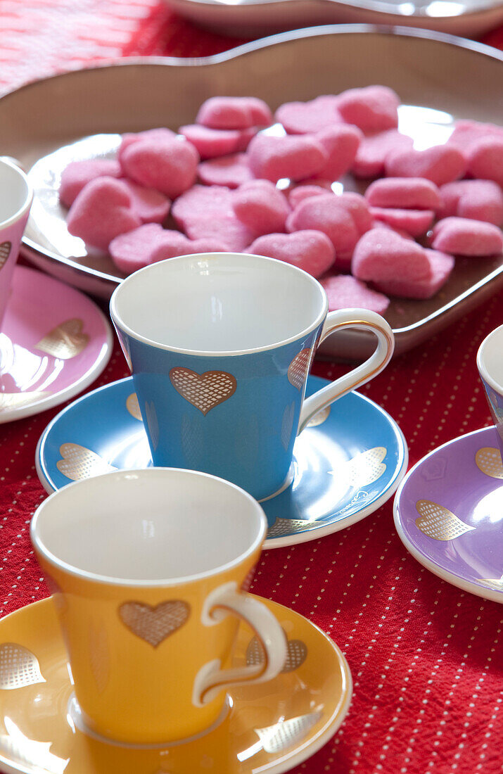 Tasse und Untertasse und rosa herzförmige Süßigkeiten auf dem Tisch in einem Haus in den Cotswolds UK