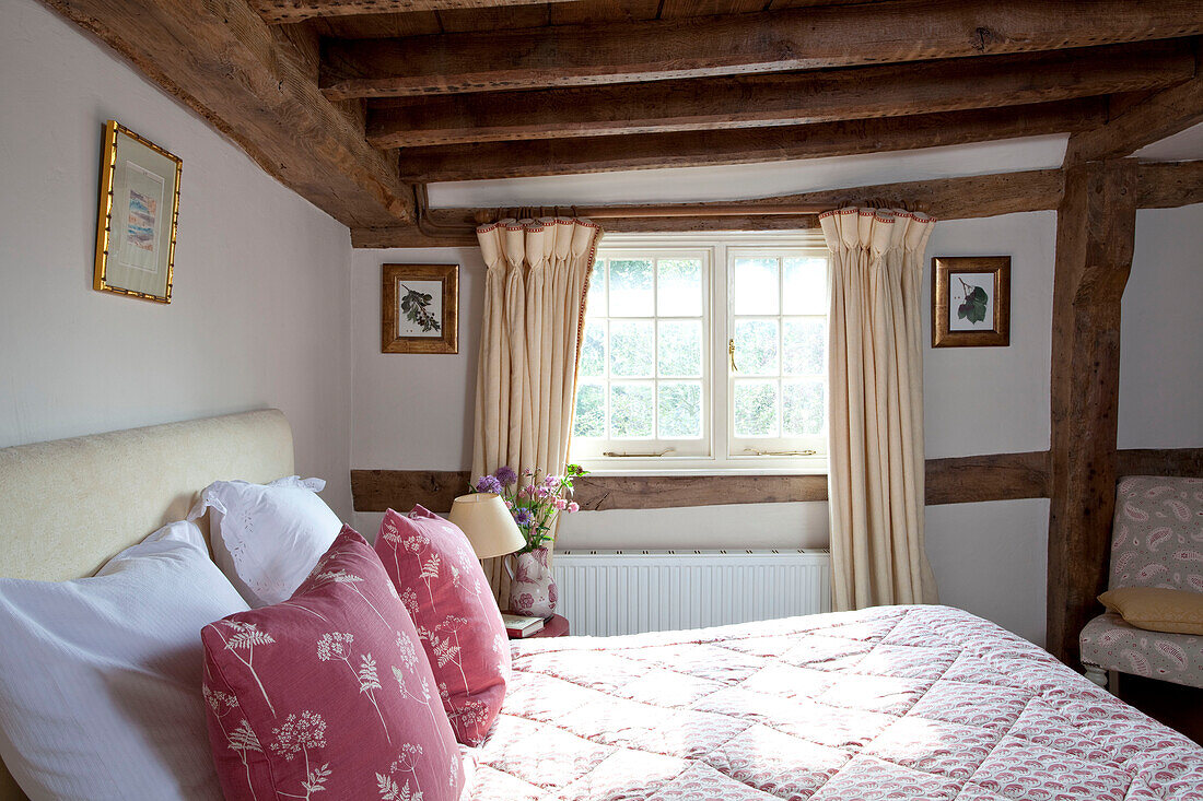 Rosa Blumenkissen auf dem Bett in einem Fachwerkhaus in East Sussex, England, Vereinigtes Königreich