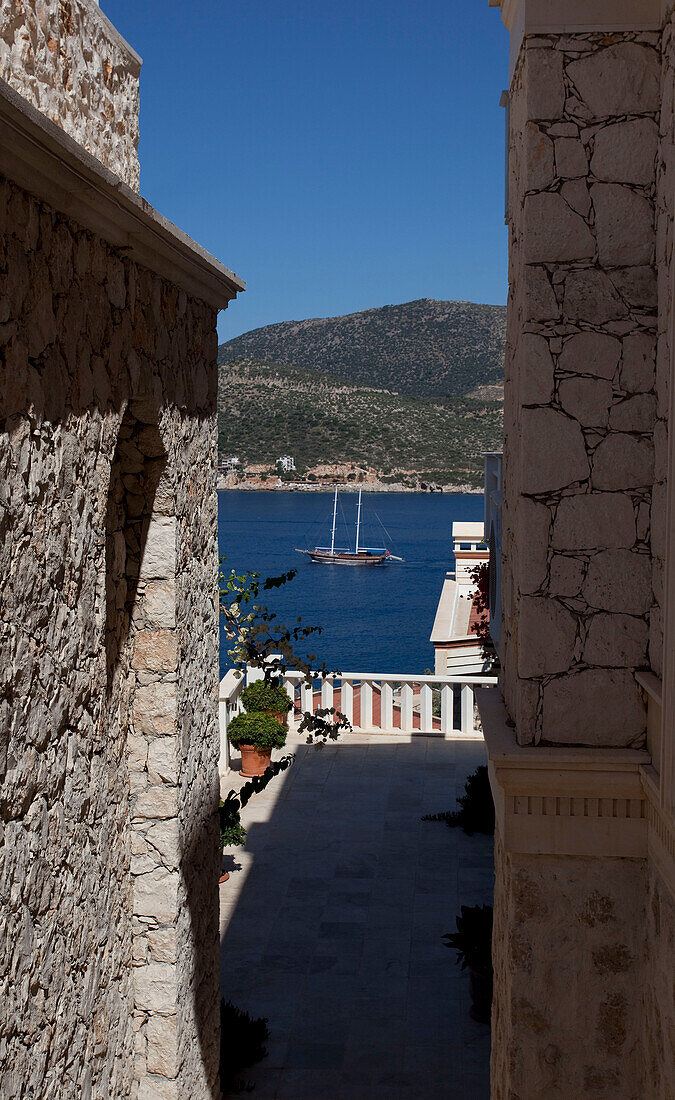 View of sailing boats beyond balcony terrace of stone holiday villa, Republic of Turkey