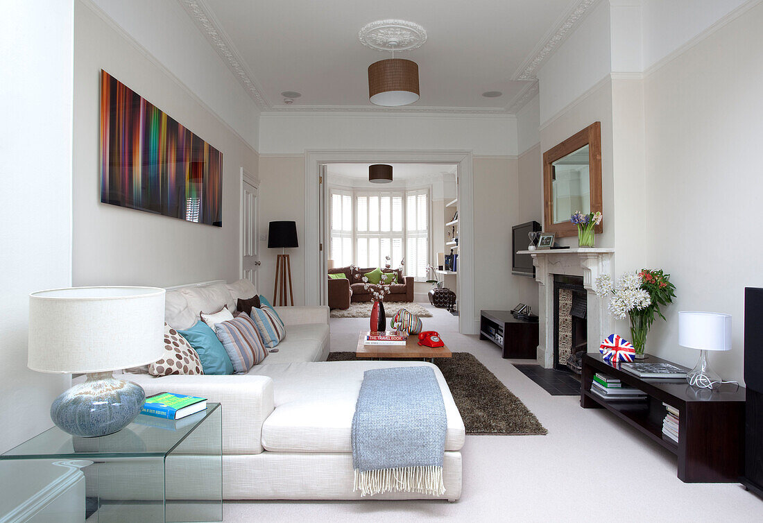 Hellblaue Decke auf weißem Sofa unter moderner Kunst in einem Doppelzimmer in einem modernen Haus in London, UK