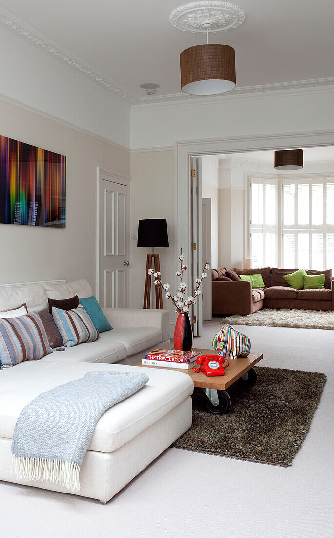 Light blue blanket on white sofa with coffee table set on rug in double room of contemporary London home, UK