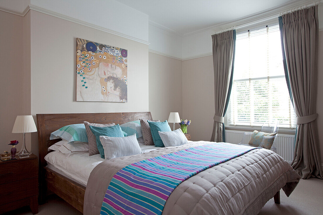 Striped blanket on double bed below artwork in contemporary London home, UK
