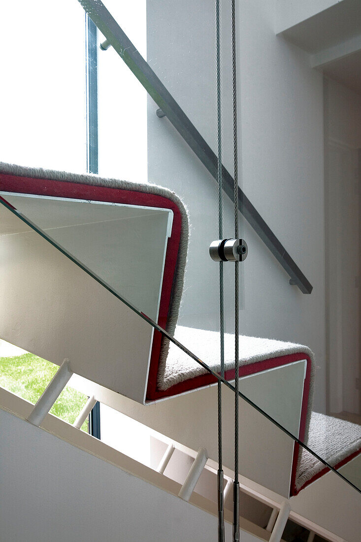 Blick durch die Glasverkleidung zum Treppenhaus mit Teppichboden in einem Haus in London, England, UK