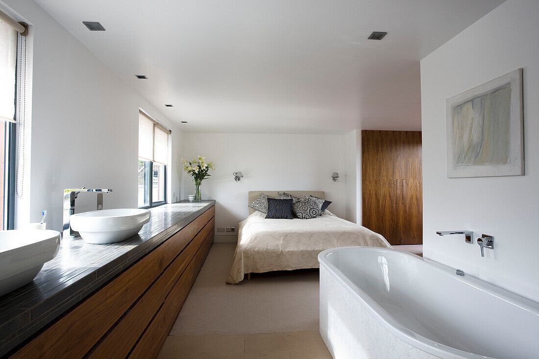 Offenes Schlafzimmer mit ausladendem Waschbecken und freistehender Badewanne in einem Einfamilienhaus in London, England, UK