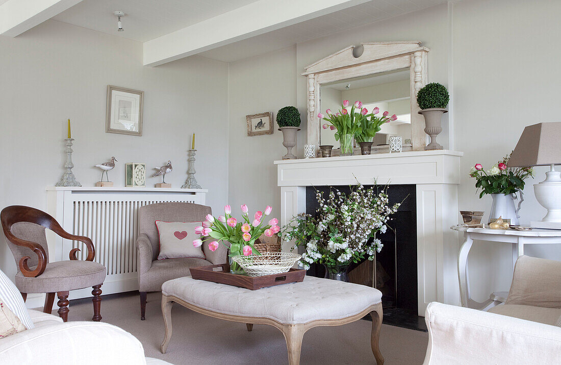 Schnittblumen und Ottomane am Kamin in einem Haus in Sussex, England