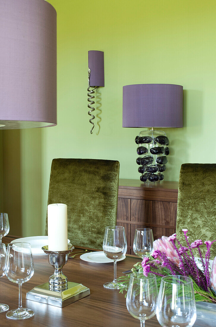 Gedeckter Holztisch mit übergroßen fliederfarbenen Lampenschirmen in einem Haus in Suffolk, Großbritannien