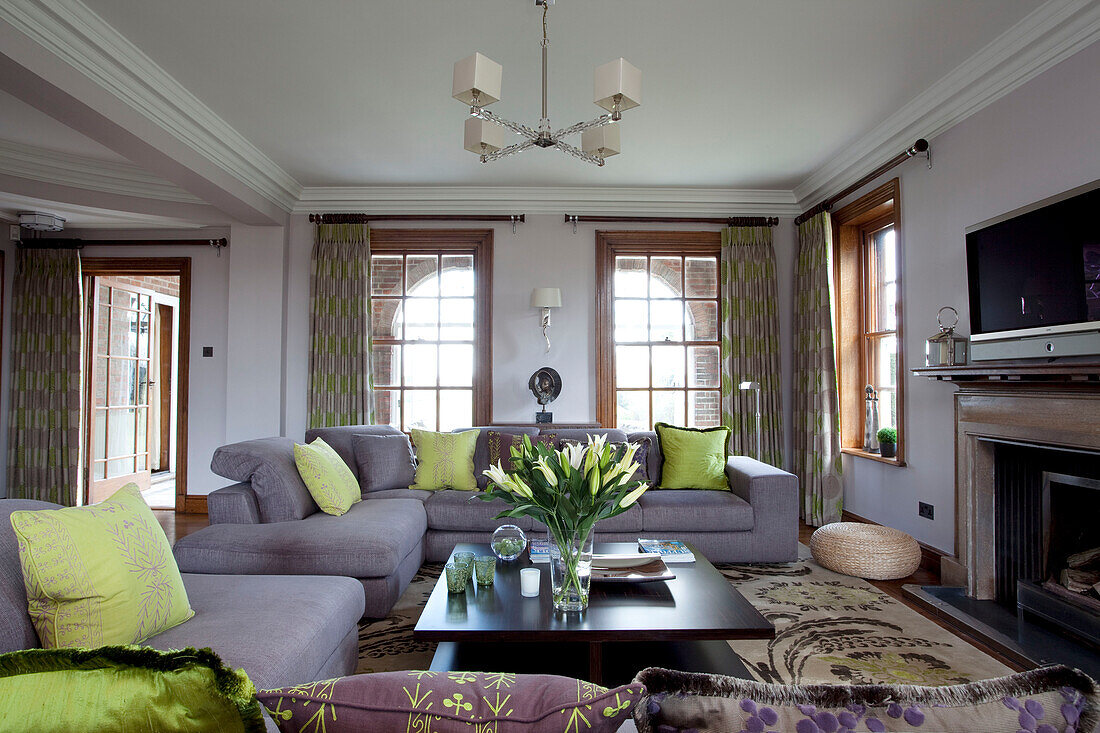 Lindgrüne Kissen auf fliederfarbenen Sofas in einem Wohnzimmer in Suffolk, UK