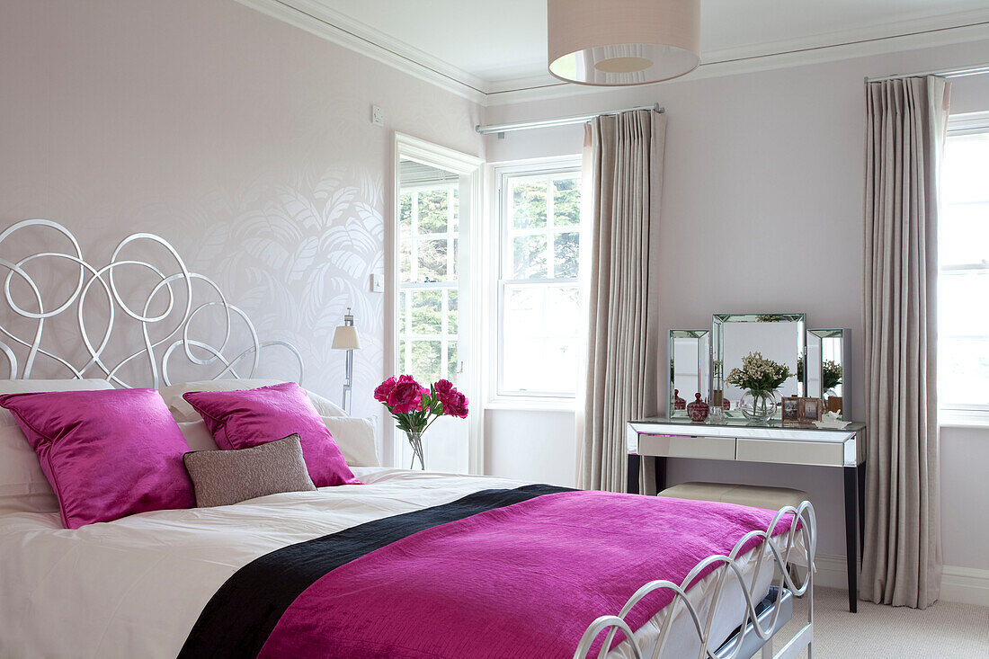 Bright pink bed covers on metal latticed bed in Suffolk home UK