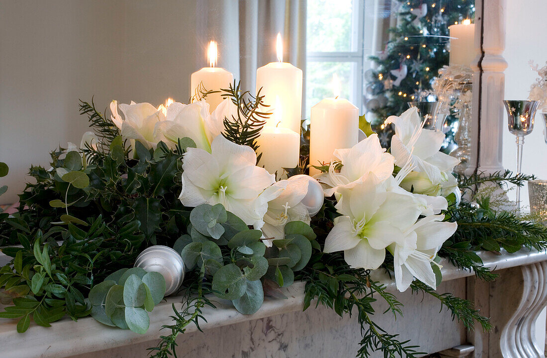 Beleuchtete Kerze und weihnachtliche Blumengirlande auf einem Marmormantel in einem Londoner Haus UK