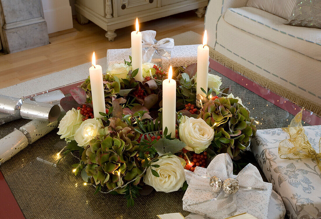 Lit candles and floral Christmas wreath on coffee table in living room of London home, UK