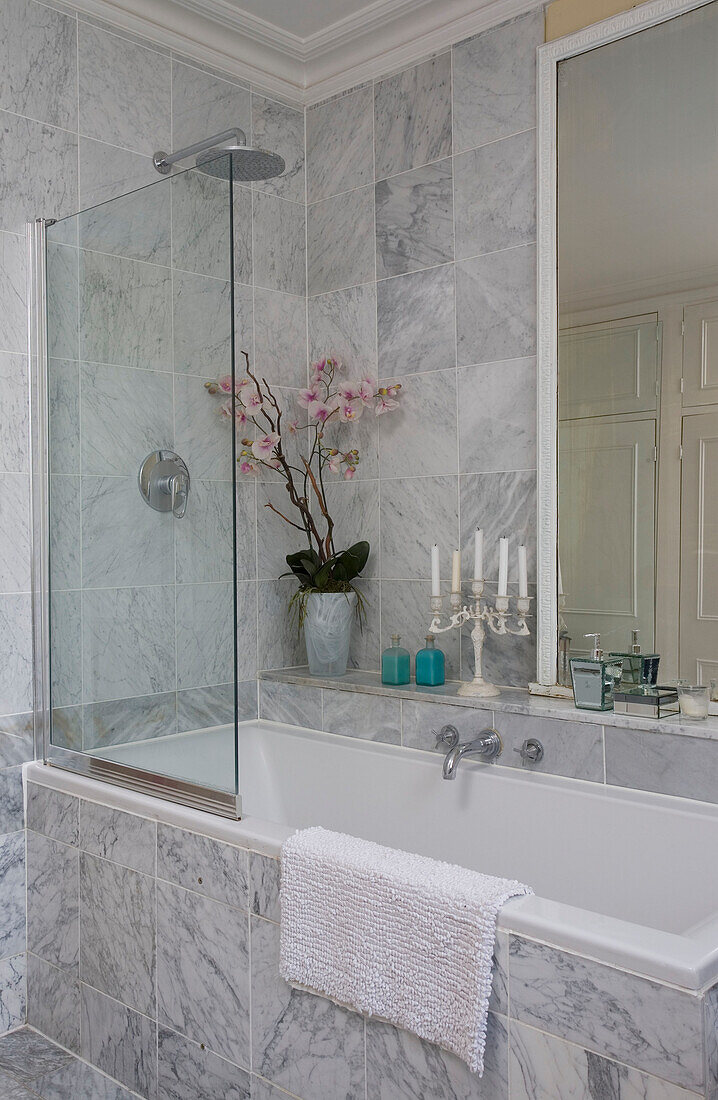 Marble tiled bathroom with glass shower screen and Orchid