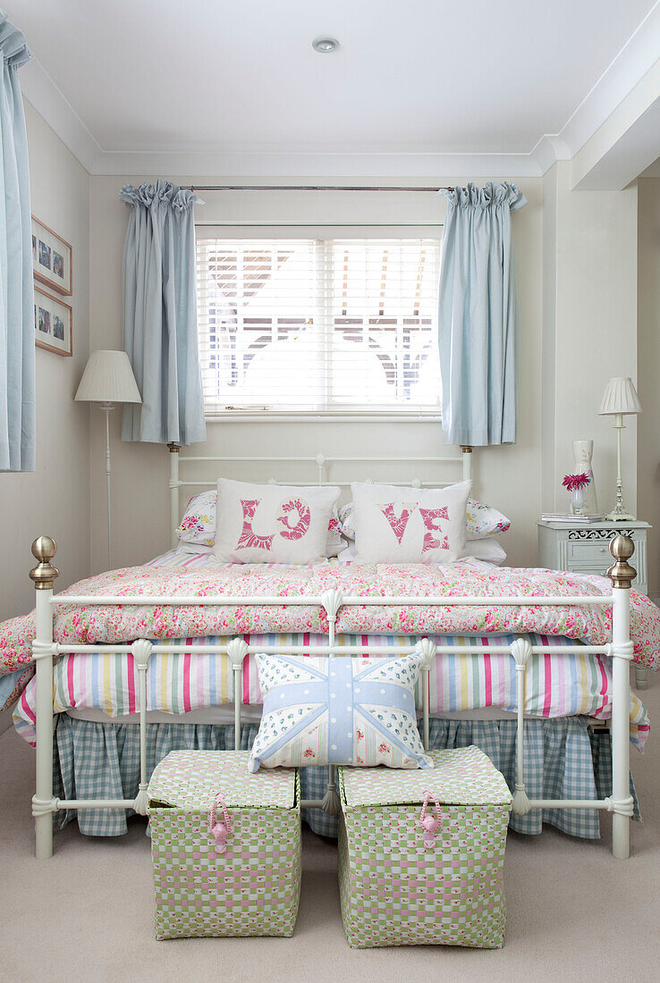 "Hellblaue Vorhänge und Kissen mit dem Wort Love"" in einem pastellfarbenen Schlafzimmer in einem Haus in Berkshire, England, UK"""