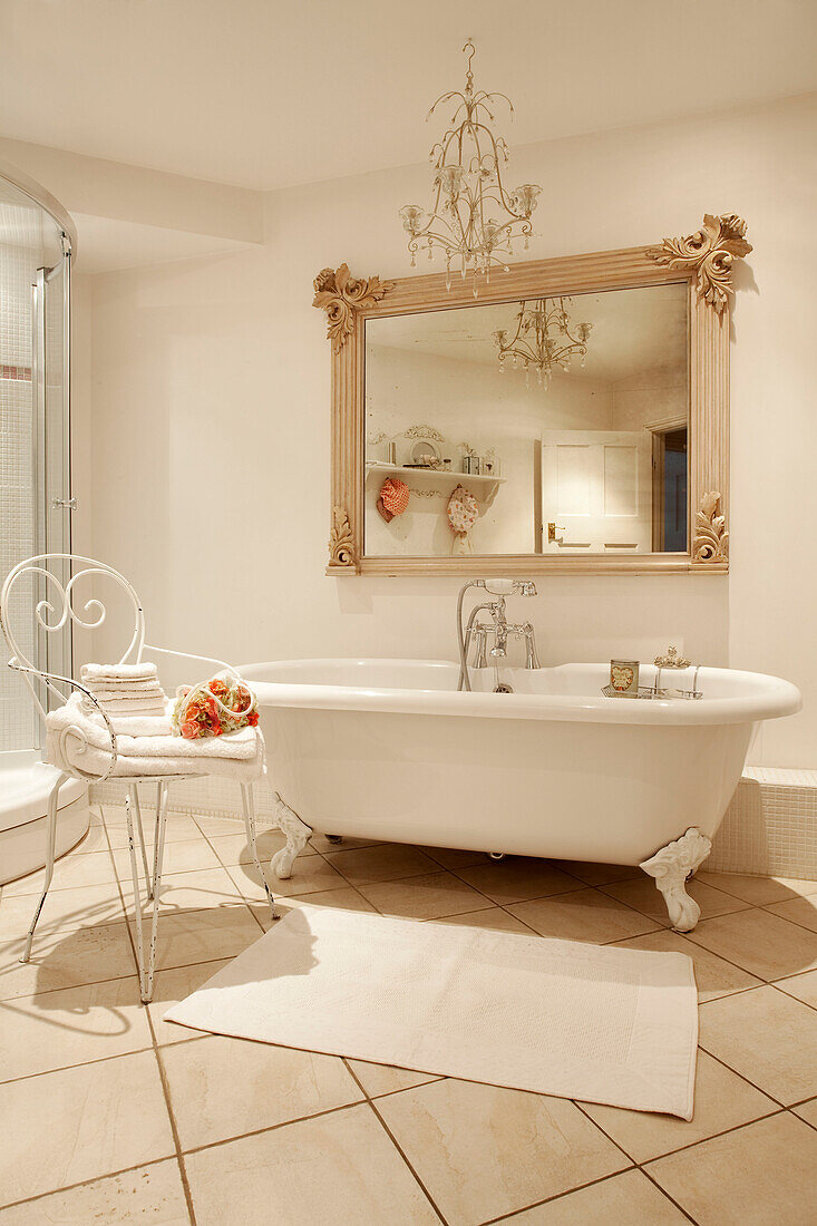 Metallstuhl und freistehende Badewanne mit antikem Spiegel in einem klassischen Haus in Berkshire, England, UK